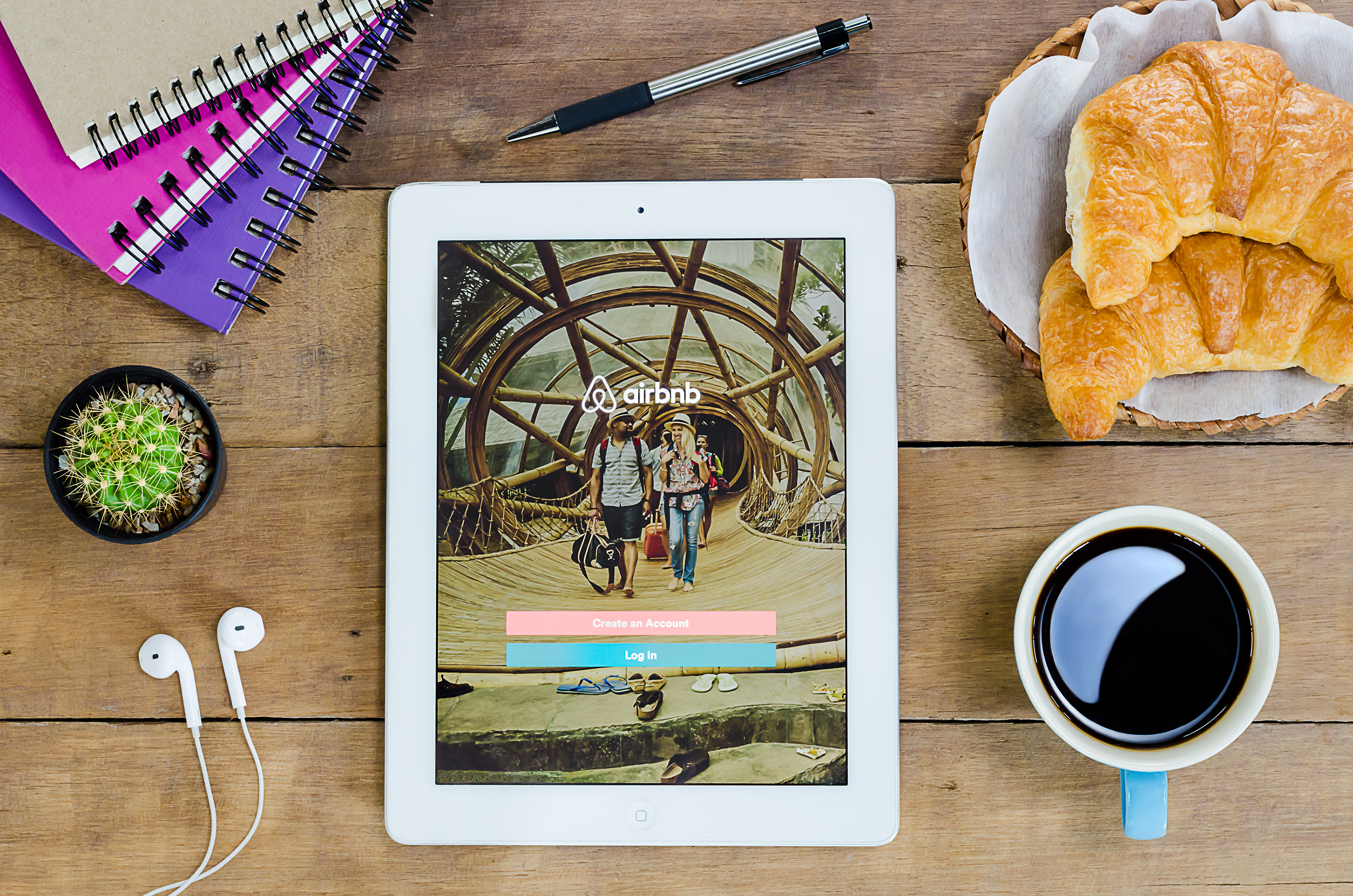 Airbnb app on tablet sitting on table with coffee and croissants