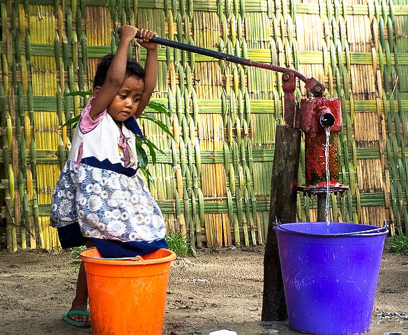 Gril pumps water from well Madagascar photo